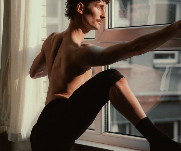 Silhouette of a man stretching against a sunrise, symbolizing balance and energy.